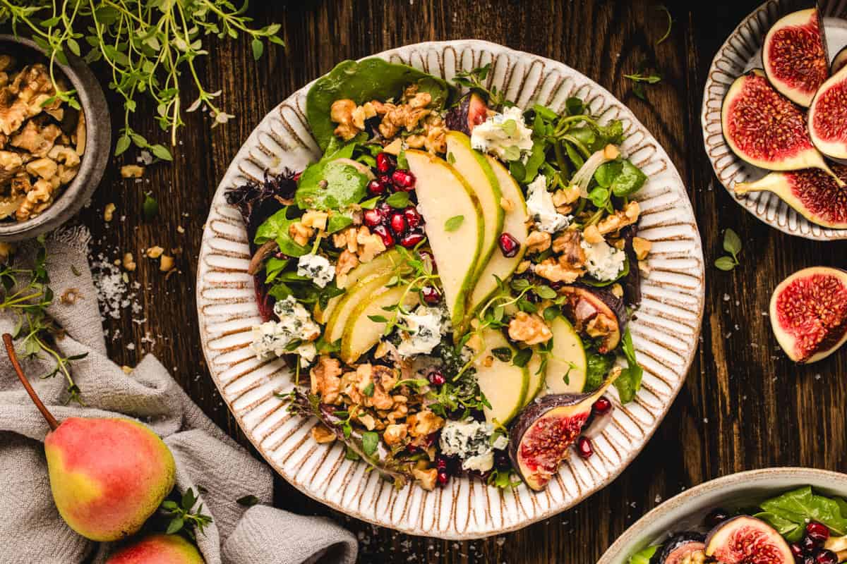 Winter Pear Salad Winter Pear Salad with mixed greens, fresh pears, figs, blue cheese, and walnuts - on a white plate.
