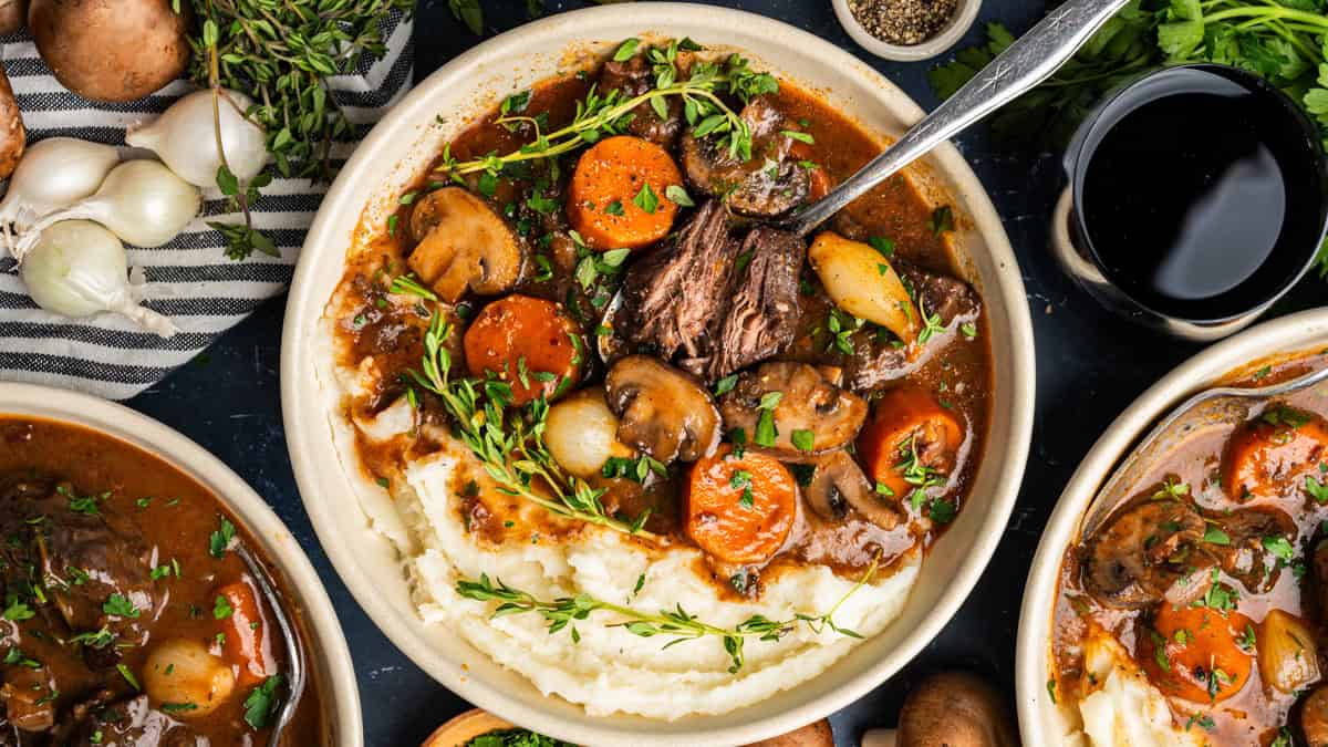 The Best Make-Ahead Beef Bourguignon for Entertaining Beef Bourguignon with mashed potatoes in a white bowl.