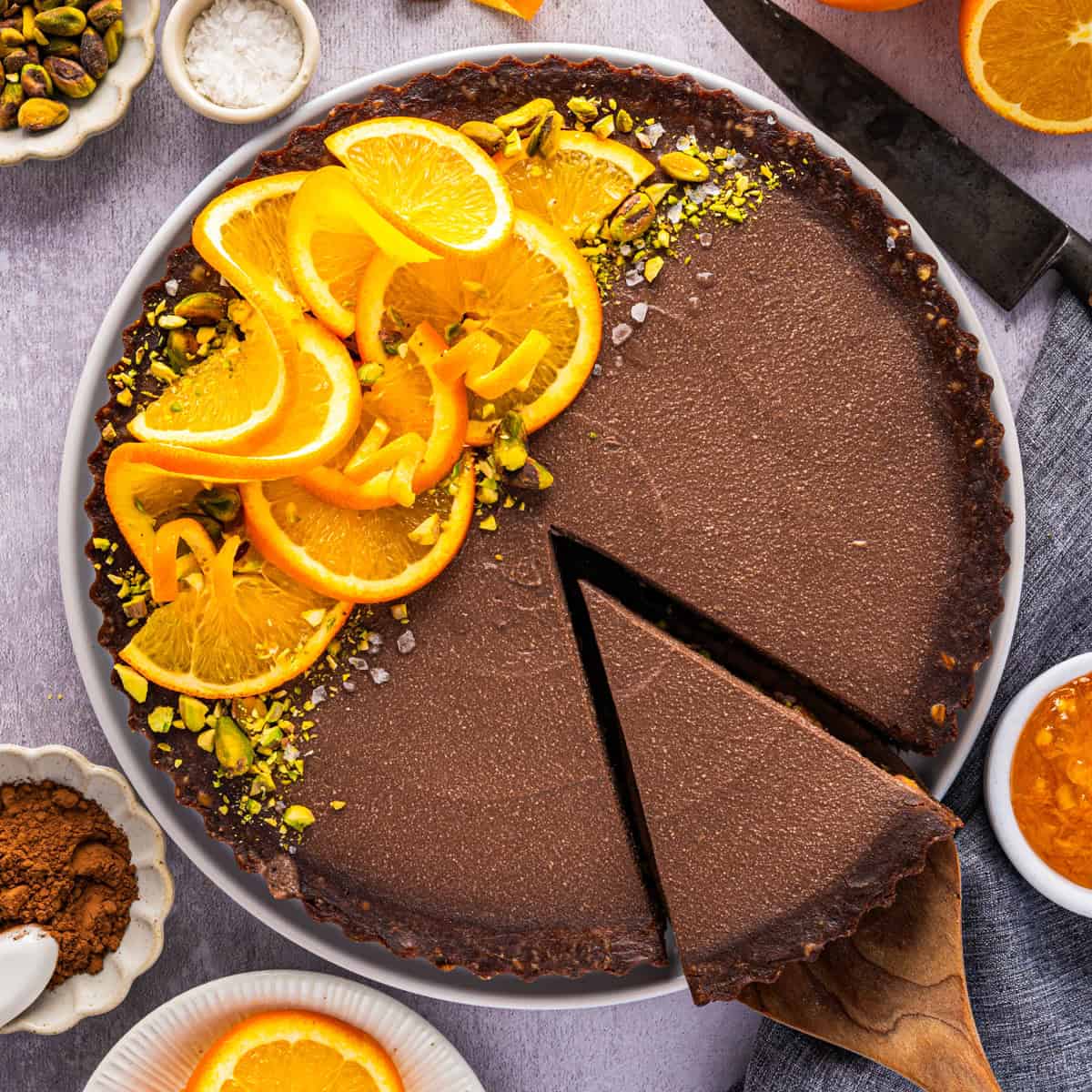 Chocolate Orange Tart (half of it is topped with fresh orange slices, chopped and whole pistachios, and sea salt).