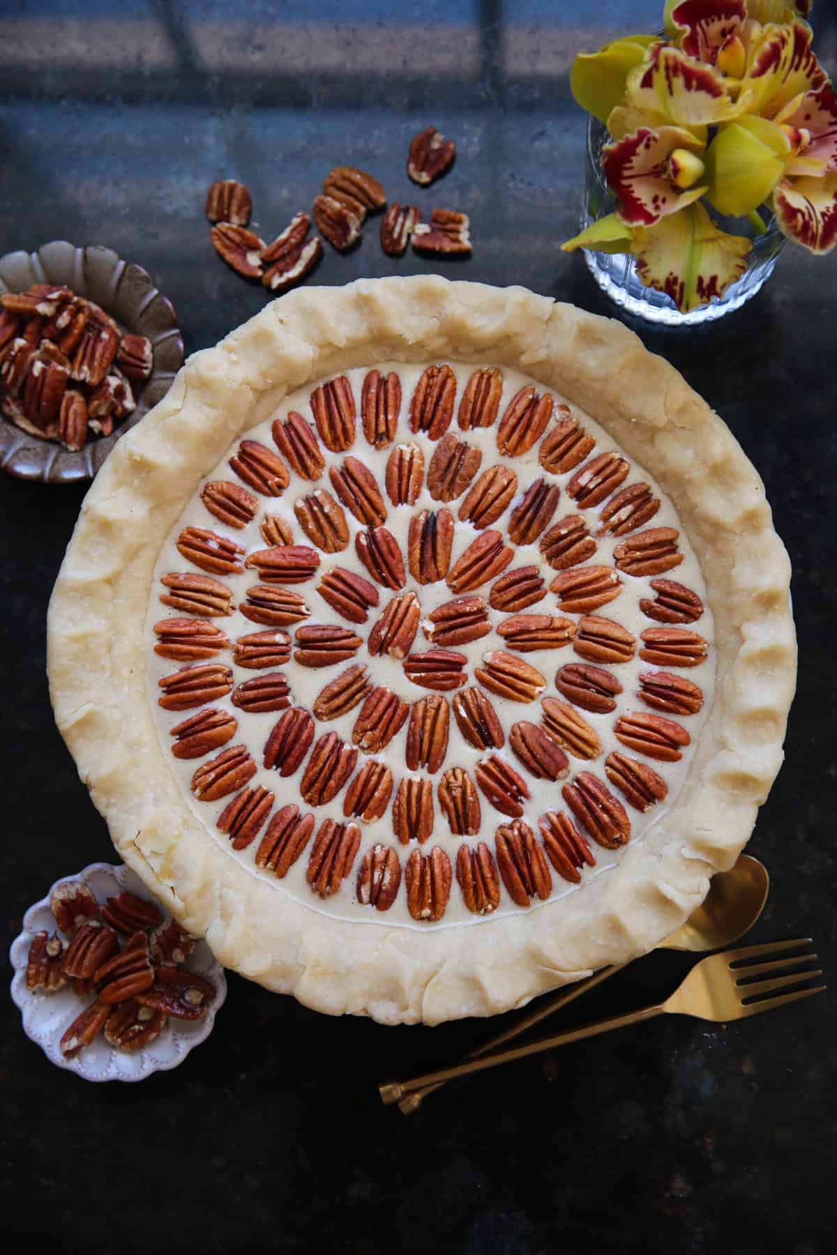 Classic Homemade Pecan Pie (completely assembled in a pie dish but unbaked) Unbaked pecan pie with pecans arranged on top in a pie dish.