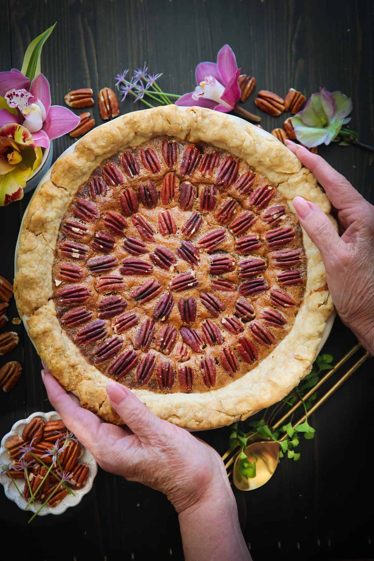 Classic Homemade Pecan Pie Pecan pie with two hands holding the pie dish.