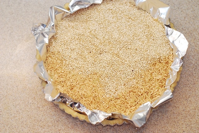 adding pie weights (quinoa and rice) on top of aluminum foil and tart crust
