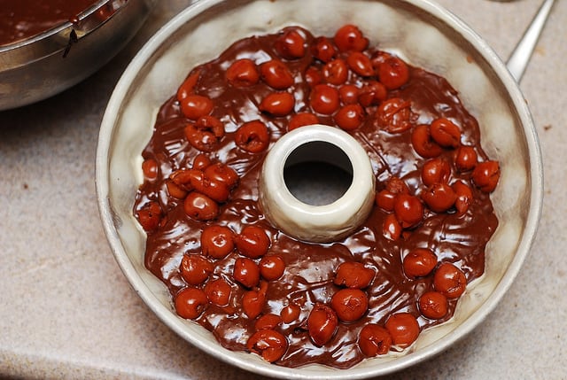 filling bundt pan with batter and alcohol soaked cherries