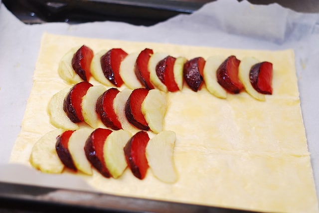 plums and apples on puff pastry sheet