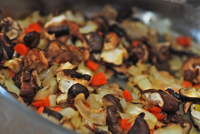 chopped vegetables (mushrooms, onions, carrots) in a stainless steel pan 