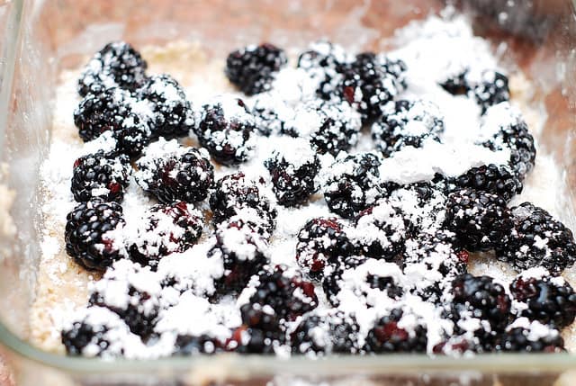 Sprinkle sugar on top of blackberries