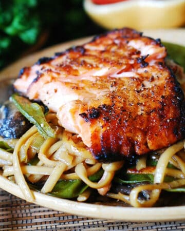 Asian salmon with noodles, mushrooms, and snow peas - on a plate.