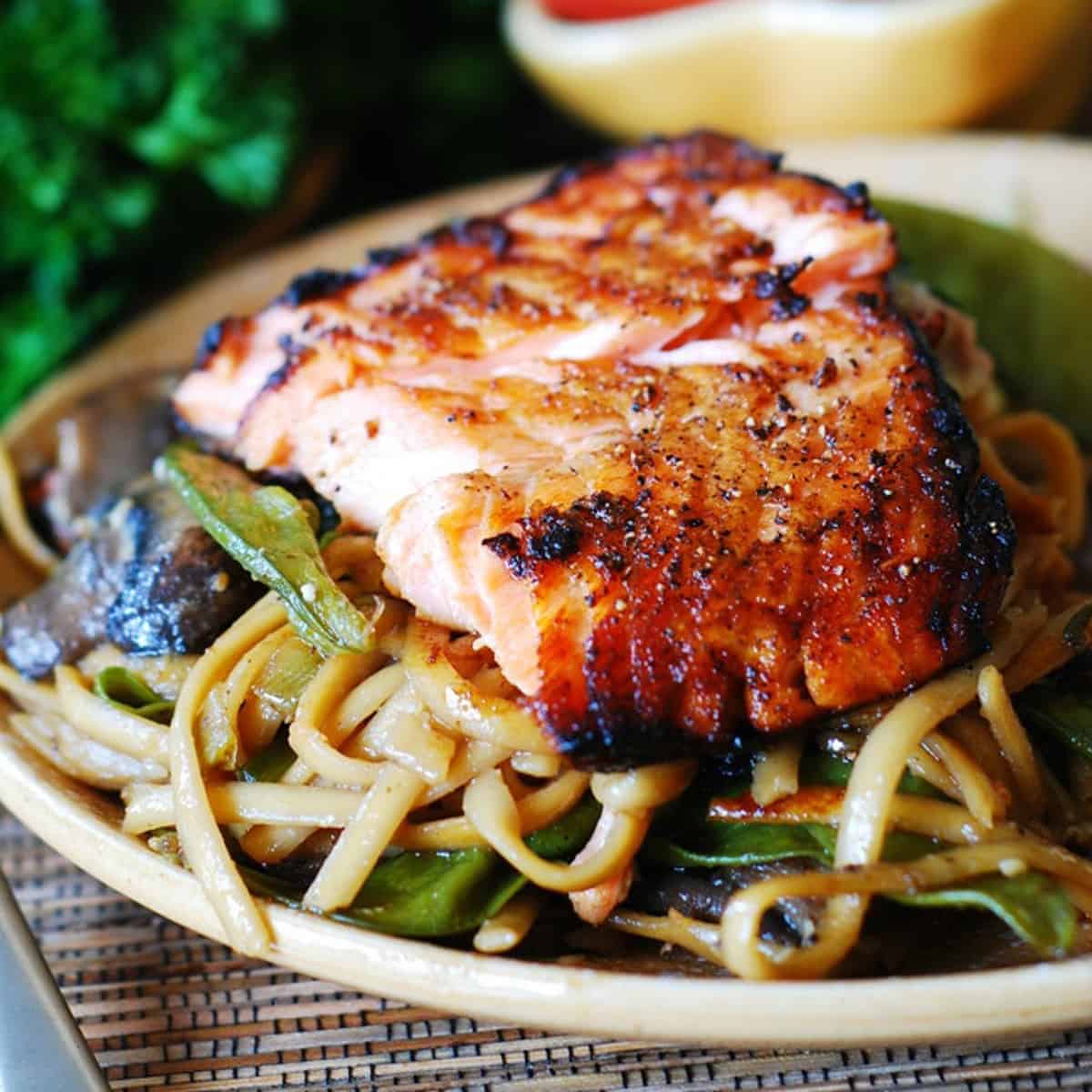 Asian salmon with noodles, mushrooms, and snow peas - on a plate.
