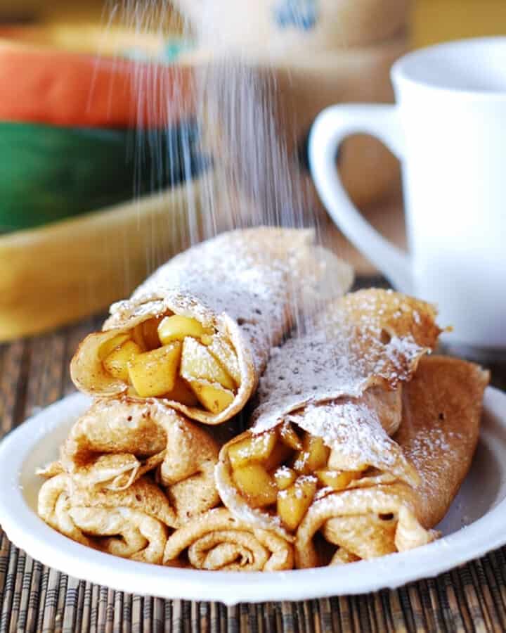 Crepes stuffed with cooked apple chunks with cinnamon - on a plate.