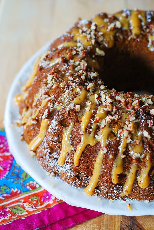 Apple Pumpkin Bundt Cake with Caramel Drizzle and Chopped Pecans on a white plate