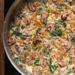 creamy caramelized onion sauce with spinach and mushrooms in a stainless steel pan.