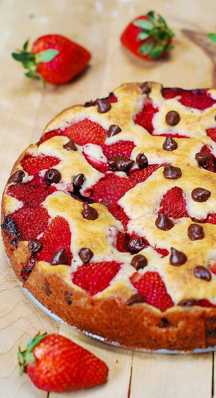 strawberry chocolate chip cake on a large wooden cutting board