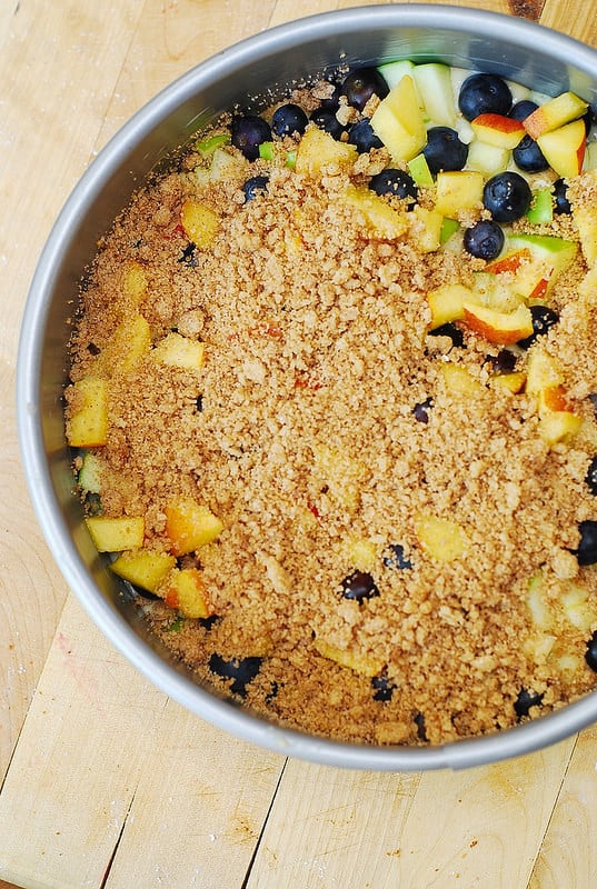 top the fruit and berries with crumb topping in springform pan