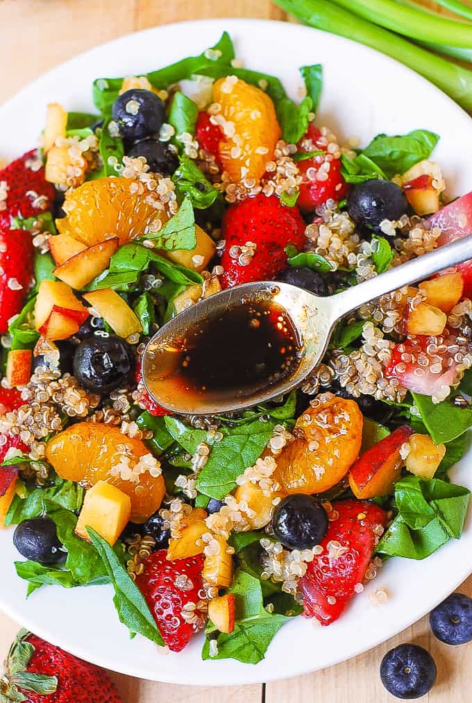 Quinoa salad with spinach, strawberries, blueberries, peaches, mandarin oranges, green onions and balsamic salad dressing