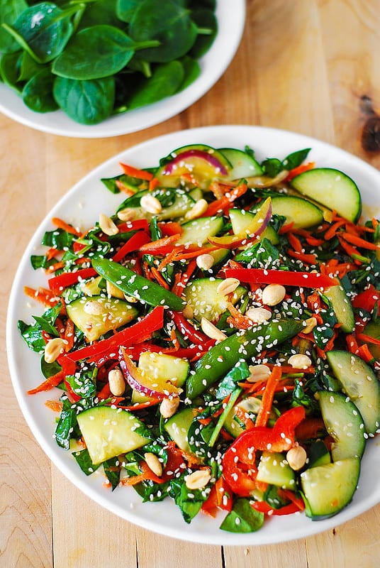 Crunchy Asian Salad with vegetables: spinach, cucumbers, red bell pepper, carrots, sugar snap peas topped with roasted peanuts and sesame seeds