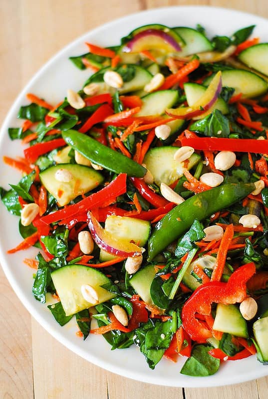 Crunchy Asian Salad with vegetables: spinach, cucumbers, red bell pepper, carrots, sugar snap peas