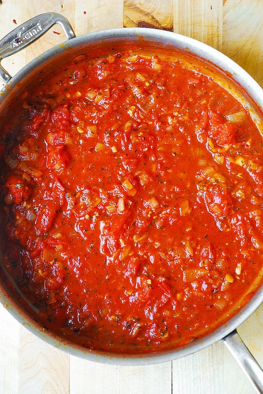 adding crushed tomatoes to the skillet