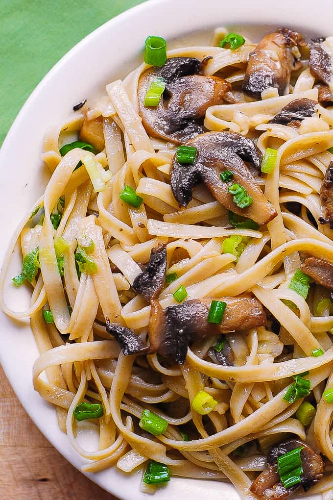 Garlic Mushroom Fettuccine Pasta with Butter, Parmesan Cheese, Green Onions on a white plate