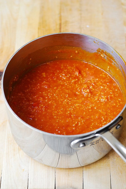Adding pumpkin, tomatoes, quinoa to the pot (process shot)