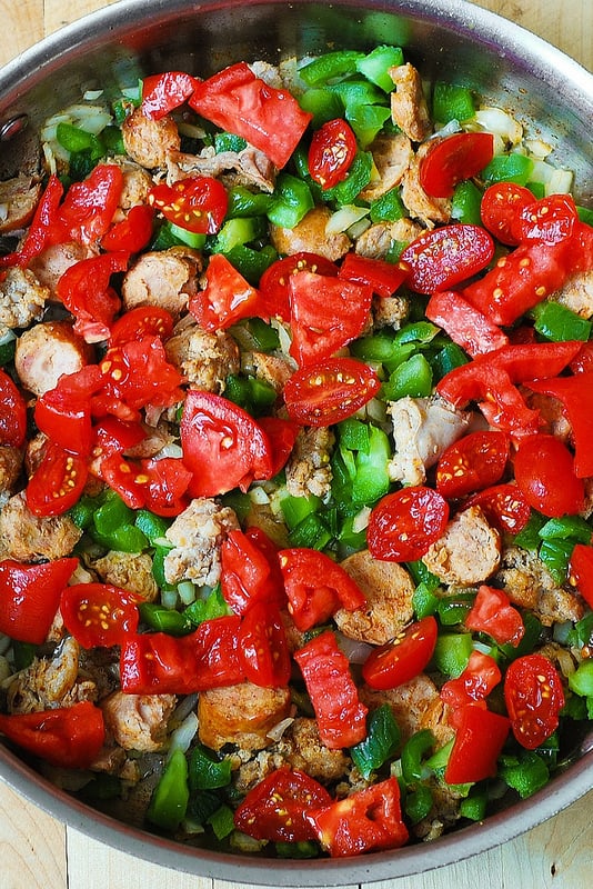 adding more tomatoes to the pasta skillet