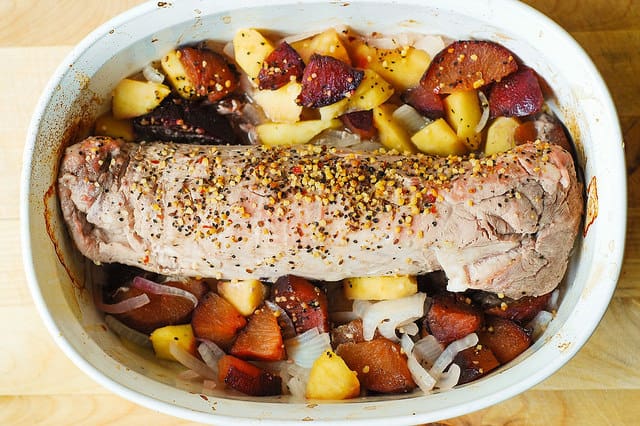 oven roasted pork tenderloin with apples and plums in a casserole dish after roasting (process shot)