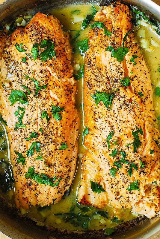2 Trout fillets with Garlic Lemon Butter Herb Sauce in a stainless steel skillet