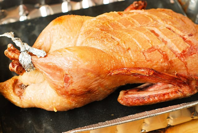 roasted duck scored breast side up in a roasting pan