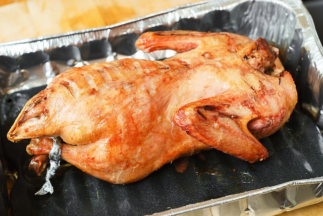 roasted duck with the breast side down in a large roasting pan