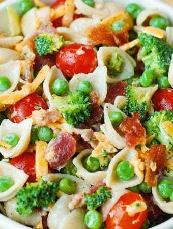 Broccoli Bacon Ranch Pasta Salad with Cherry Tomatoes, Sweet Peas, Cheddar Cheese - in a white bowl.