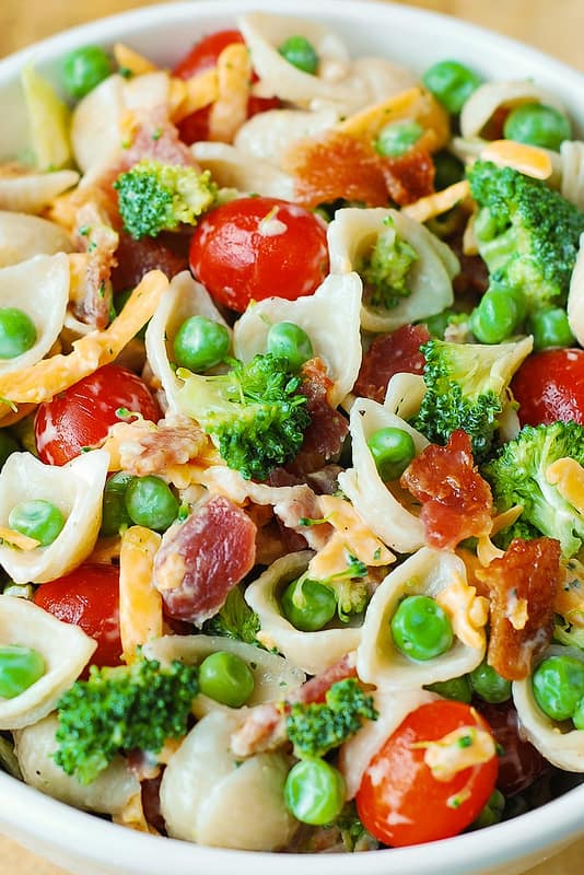 Broccoli Bacon Ranch Pasta Salad with Cherry Tomatoes, Sweet Peas, Cheddar Cheese - in a white bowl.