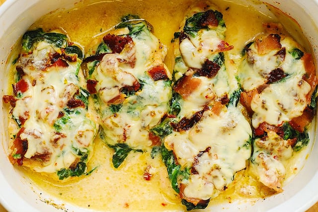 chicken bake with sun-dried tomatoes, creamed spinach, and bacon in a casserole dish