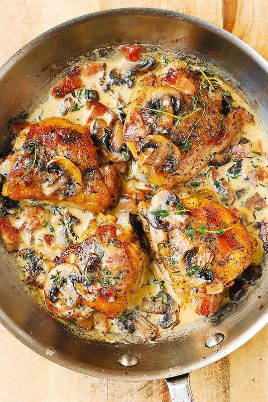 4 Chicken Thighs with Creamy Bacon Mushroom Thyme Sauce in a stainless steel skillet