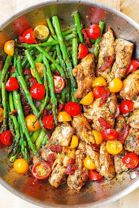 One-Pan Pesto Chicken and Veggies (asparagus and cherry tomatoes) in a stainless steel pan
