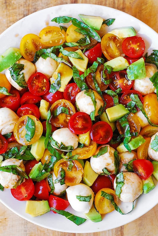 Tomato Basil Avocado Mozzarella Salad with Balsamic Dressing - on a white plate.