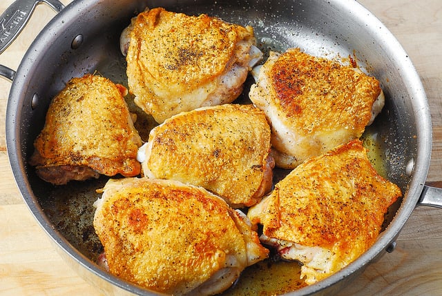 brown chicken thighs in a large skillet in olive oil with salt and pepper