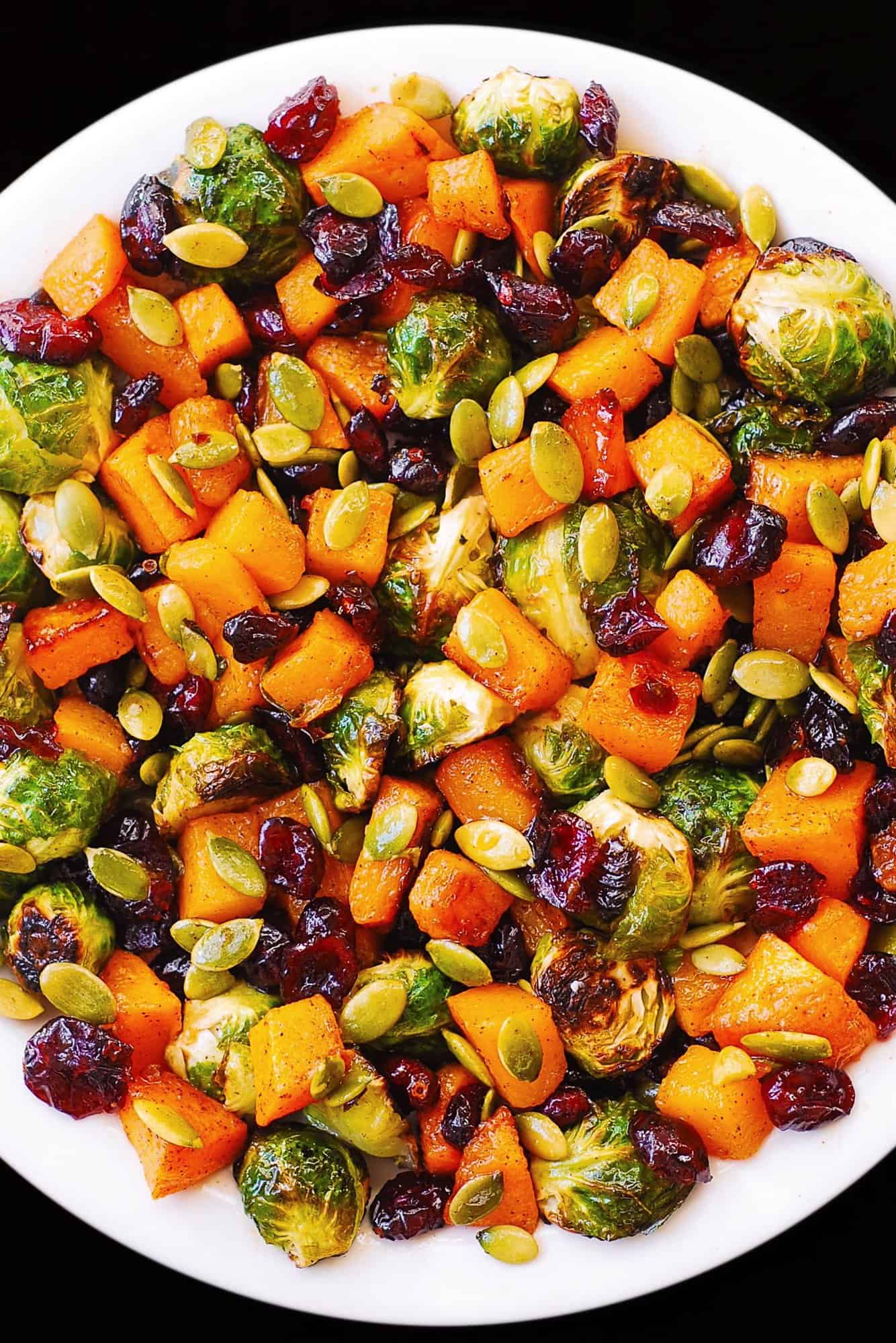 Roasted Brussels Sprouts Salad with Maple Butternut Squash, Pumpkin Seeds, and Cranberries - on a white plate.