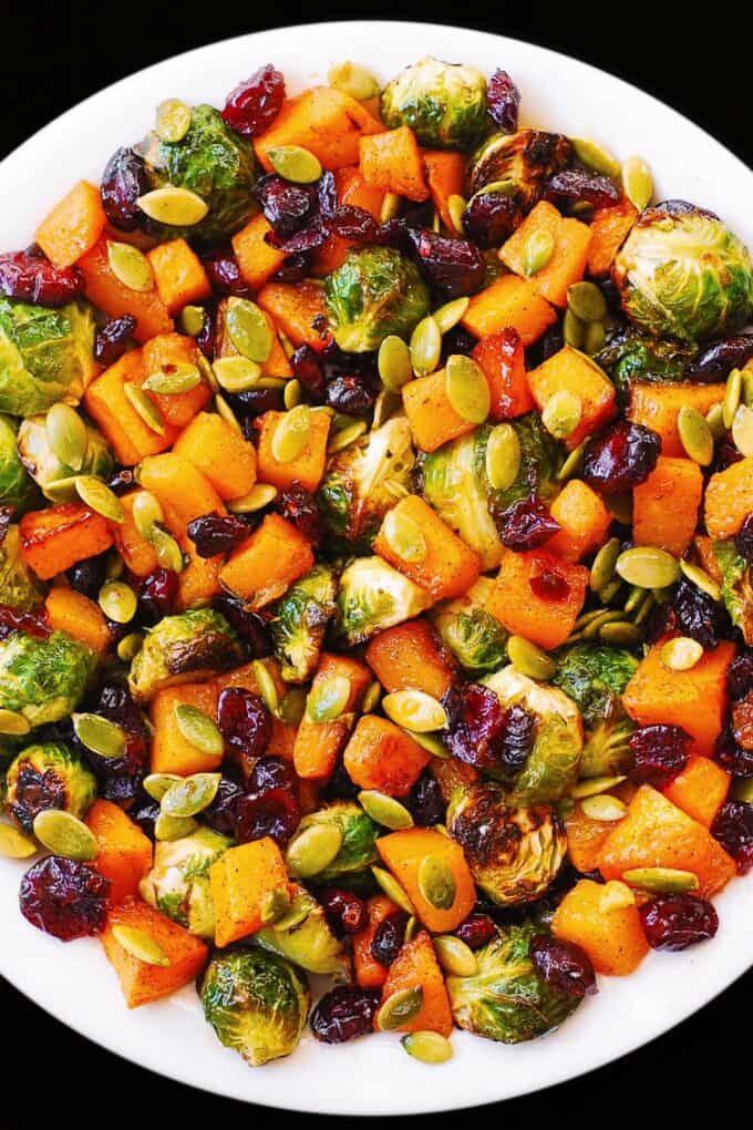 Roasted Brussels Sprouts Salad with Maple Butternut Squash, Pumpkin Seeds, and Cranberries on a white plate.