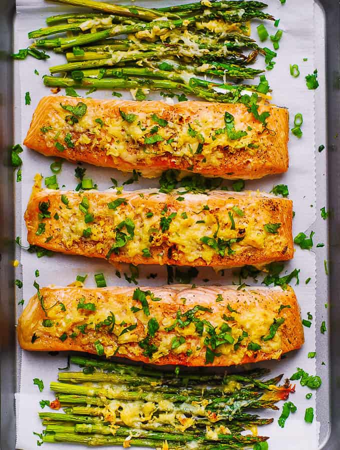 Parmesan Salmon and Asparagus on parchment paper on a baking sheet