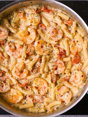 shrimp pasta with creamy mozzarella alfredo sauce in a stainless steel skillet