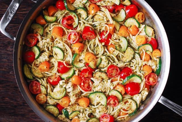 Chicken Spaghetti with Cherry Tomatoes, Zucchini, and Basil Pesto in a stainless steel skillet
