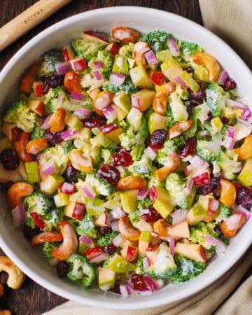 Creamy Broccoli Cashew Salad with Apples, Pears, and Cranberries - in a white bowl.