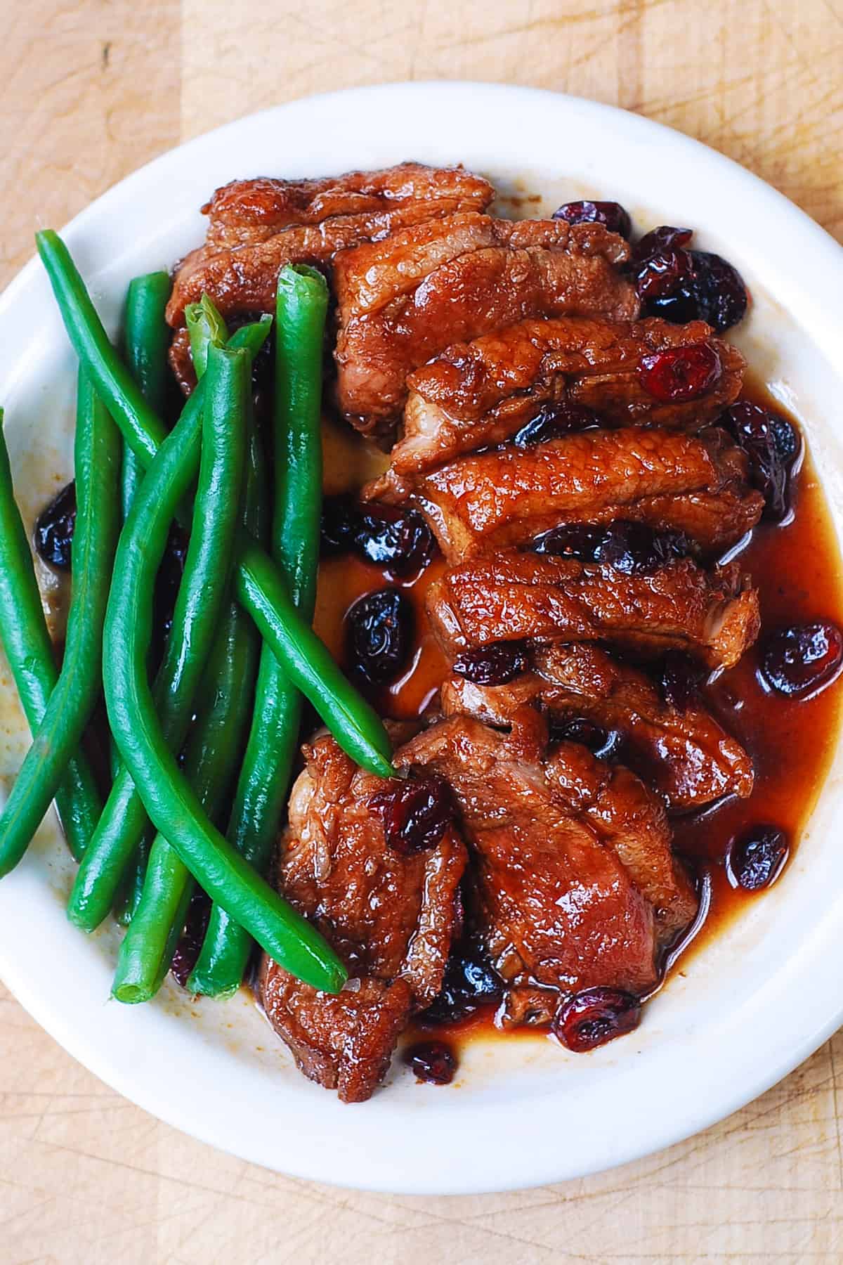 Duck Breast with Cranberry Sauce and Green Beans on a white plate.