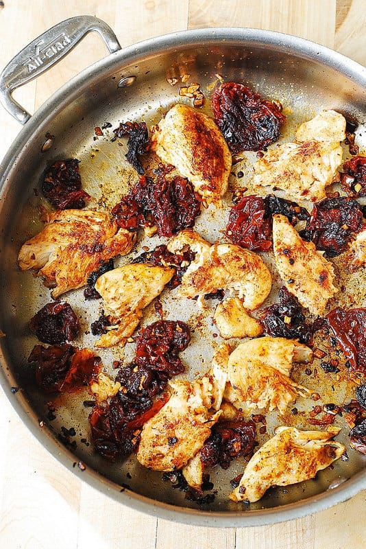 sun-dried tomatoes and cooked chicken in a stainless steel skillet