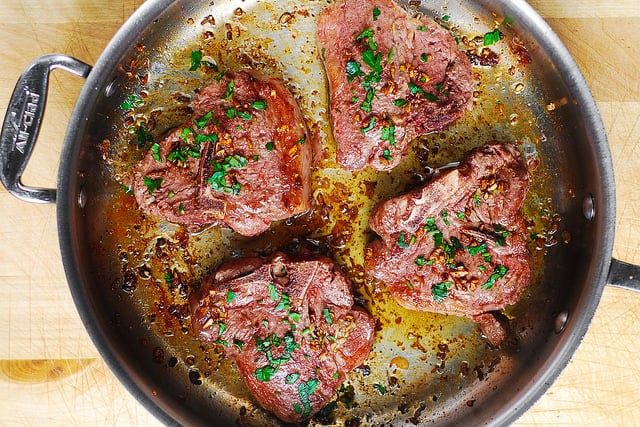 4 cooked lamb loin chops in a stainless steel pan