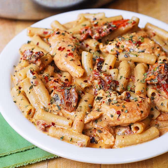chicken mozzarella penne pasta with sun-dried tomatoes on a white plate