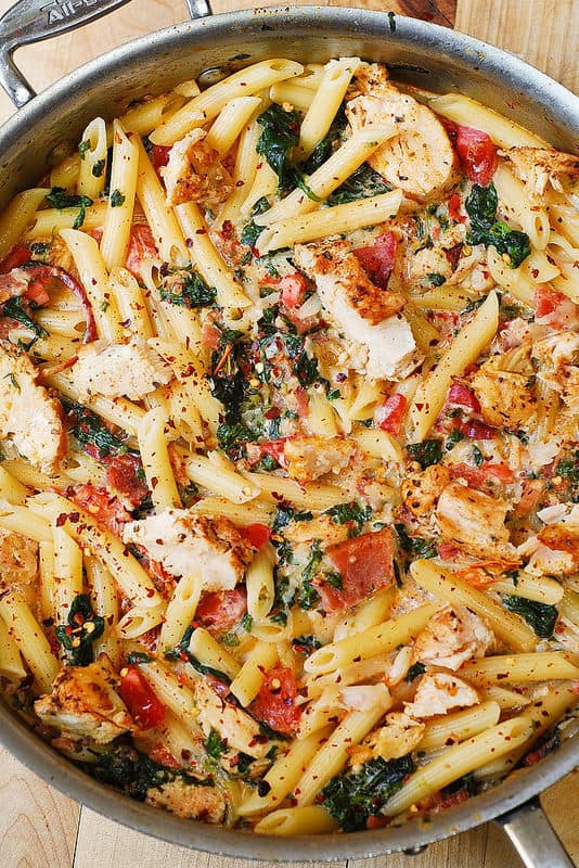 Chicken and Bacon Pasta with Spinach and Tomatoes in Garlic Cream Sauce in a stainless steel pan