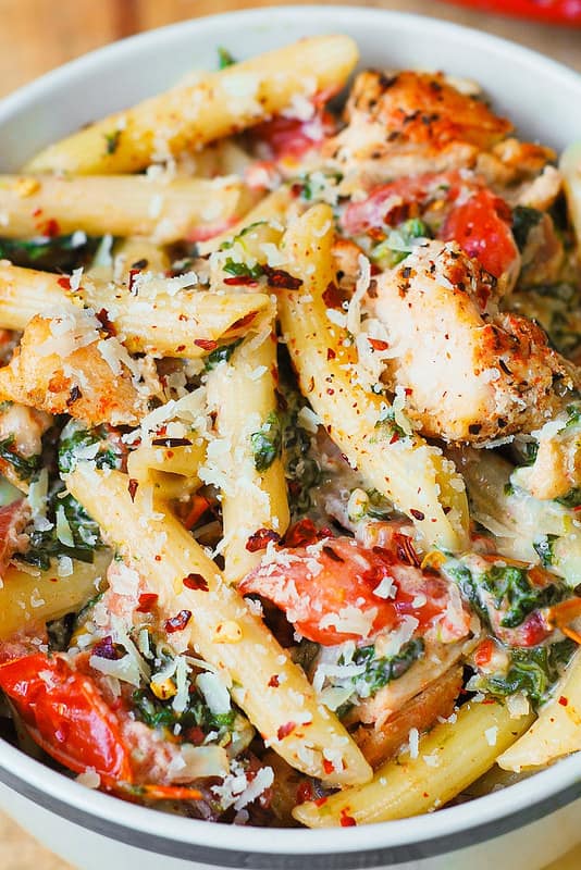 Chicken and Bacon Pasta with Spinach and Tomatoes in Garlic Cream Sauce in a white bowl