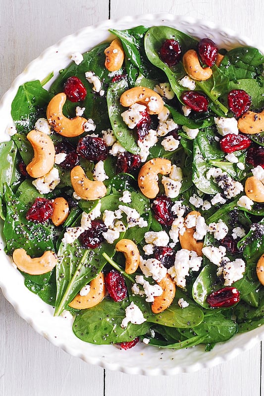 Cranberry Spinach Salad with Cashews and Goat Cheese and Lemon-Honey Poppy Seed Dressing in a white bowl