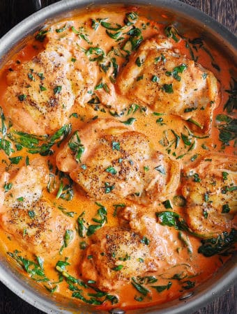 Chicken Thighs with Creamy Tomato Basil Spinach Sauce - in a stainless steel pan.