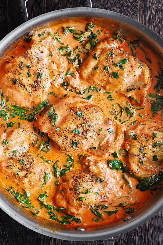Chicken Thighs with Creamy Tomato Basil Spinach Sauce - in a stainless steel pan.